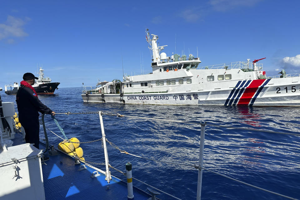 A Philippine Coast Guard member holds on a rubber fender as a Chinese coast guard vessel and suspected Chinese militia ship chases the Philippine coast guard vessel BRP Cabra while approaching Second Thomas Shoal, locally known as Ayungin Shoal, during a resupply mission at the disputed South China Sea on Friday Nov. 10, 2023. (AP Photo/Joeal Calupitan)