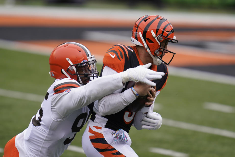 Cincinnati Bengals quarterback Joe Burrow, right, is sacked by Cleveland Browns' Myles Garrett (95) during the first half of an NFL football game, Sunday, Oct. 25, 2020, in Cincinnati. (AP Photo/Michael Conroy)