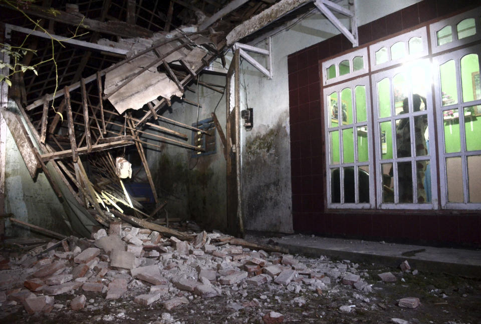 Una mujer inspecciona parte de su casa dañada por un sismo en Malan, en Java Orienal, Indonesia, el sábado, 10 de abril del 2021. El fuerte terremoto mató al menos a ocho personas y causó daños a centenares de edificios. (AP Foto/Hendra Permana)