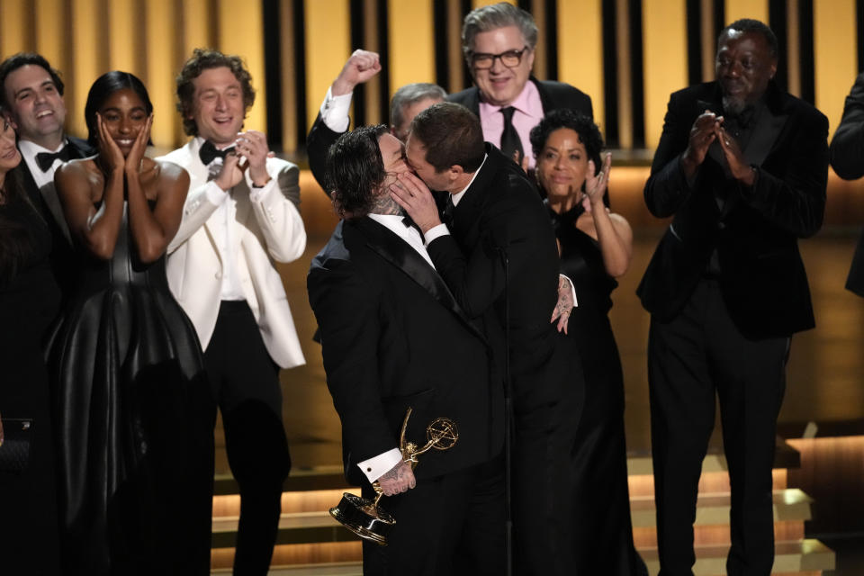 Matty Matheson, centro, y Ebon Moss-Bachrach se besan después de que "The Bear" ganara el premio a mejor comedia en la 75a edición de los Premios Emmy el lunes 15 de enero de 2024 en el Teatro Peacock de Los Ángeles. (Foto AP/Chris Pizzello)