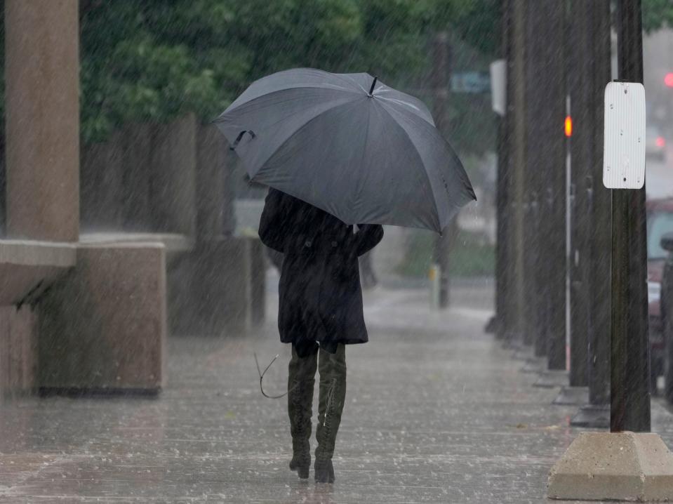 A woman shields herself from the rain with her umbrella while walking near the Milwaukee County War Memorial Center on North Lincoln Memorial Drive in Milwaukee on Sunday, Sept. 11, 2022.