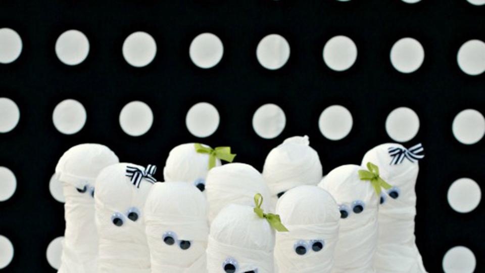 kids bowling set wrapped in toilet paper with googly eyes to resemble mummies for a halloween activity