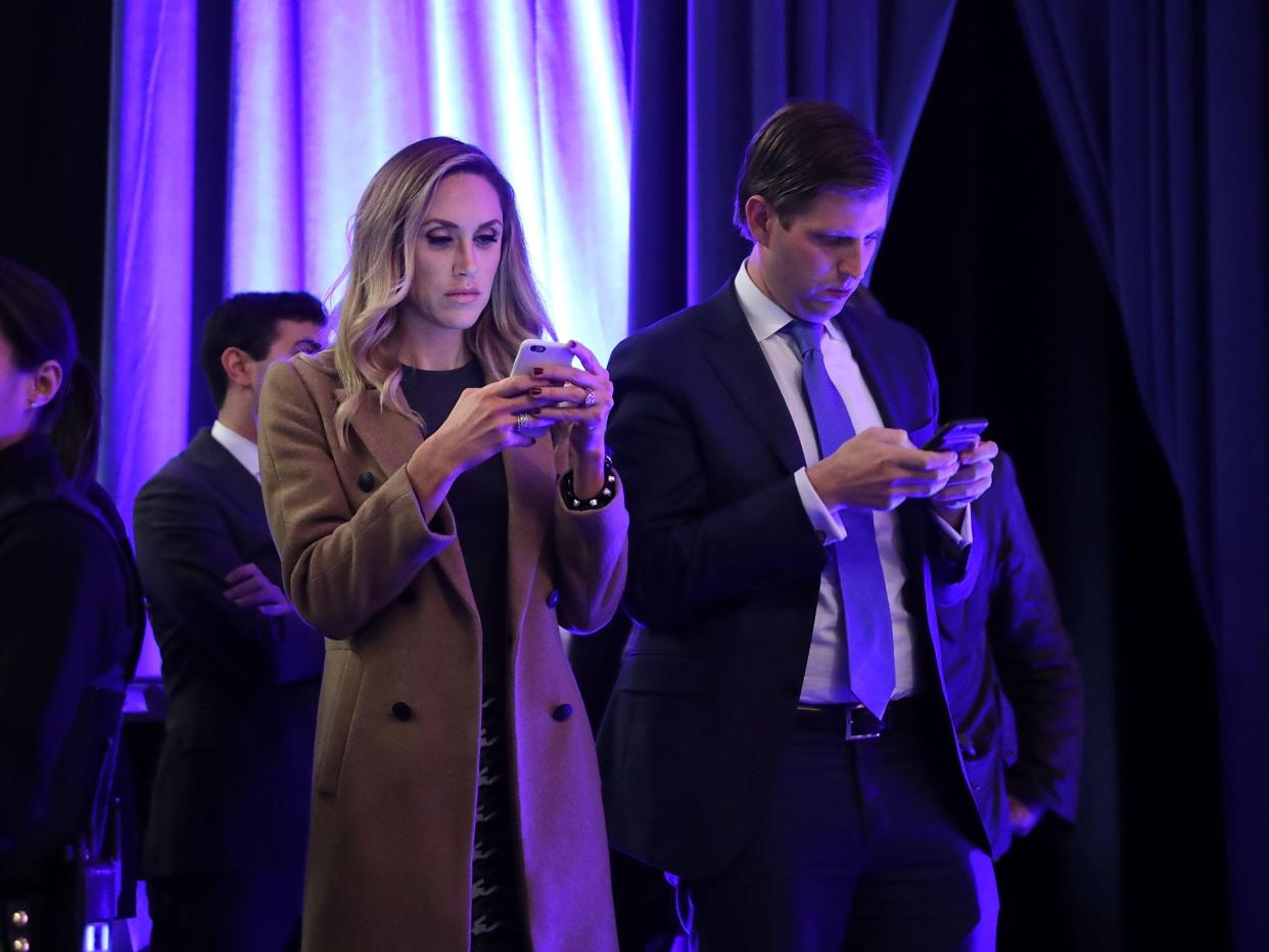 Lara Trump and Eric Trump on their phones at a campaign event before the 2016 election