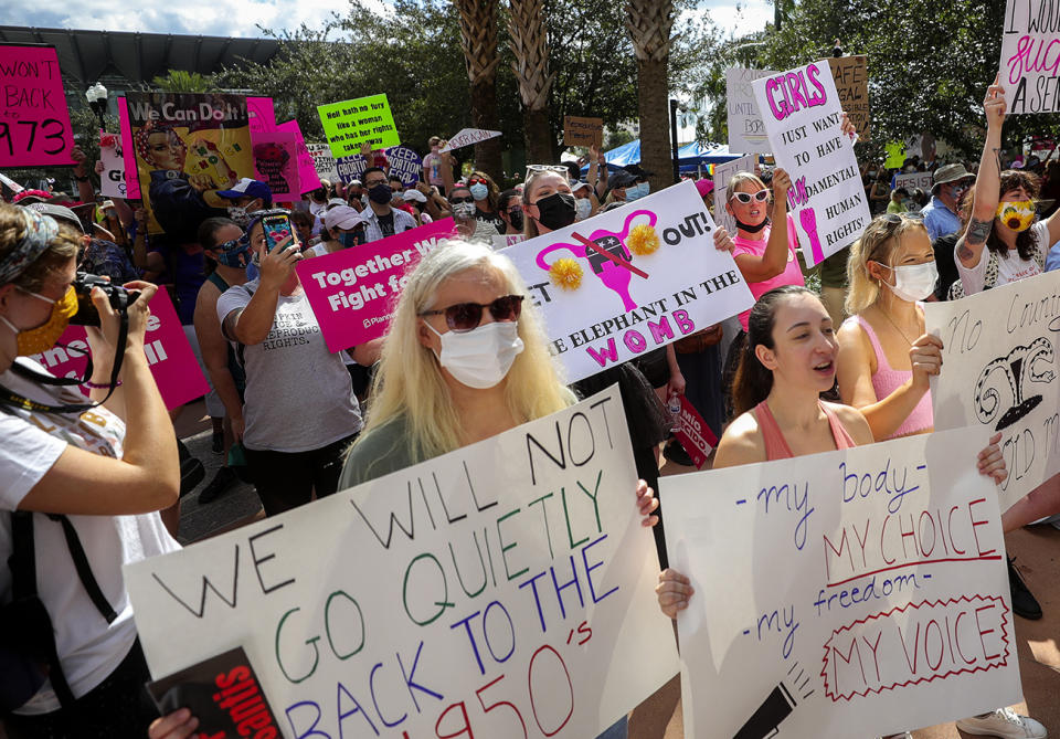 FILE - Participants wave signs as they walk back to Orlando City Hall during the March for Abortion Access on Saturday, Oct. 2, 2021, in Orlando, Fla. State-by-state battles over the future of abortion in the U.S. are setting up across the country as lawmakers in Republican-led states propose new restrictions modeled on laws passed in Texas and Mississippi even as some Democratic-controlled states work to preserve access. (Chasity Maynard/Orlando Sentinel via AP, File)