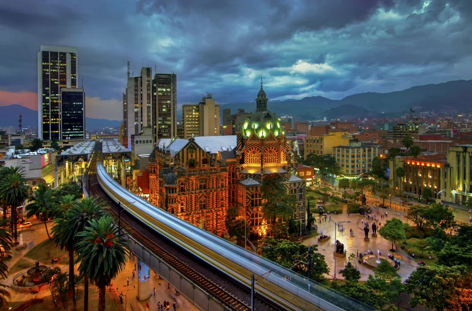 Metro elevado de Medellín está en movimiento mientras se precipita hacia la estación Parque Berrio frente al iluminado Palacio de la Cultura en la Plaza Botero en Medellín, Colombia. La Ciudad de la Eterna Primavera está ubicada en el Valle de Aburra, una región central de la Cordillera de los Andes en América del Sur. Foto: Getty Images. 