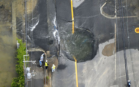 Water flows out from cracks in a road damaged by an earthquake in Takatsuki, Osaka prefecture, western Japan, in this photo taken by Kyodo June 18, 2018. Mandatory credit Kyodo/via REUTERS