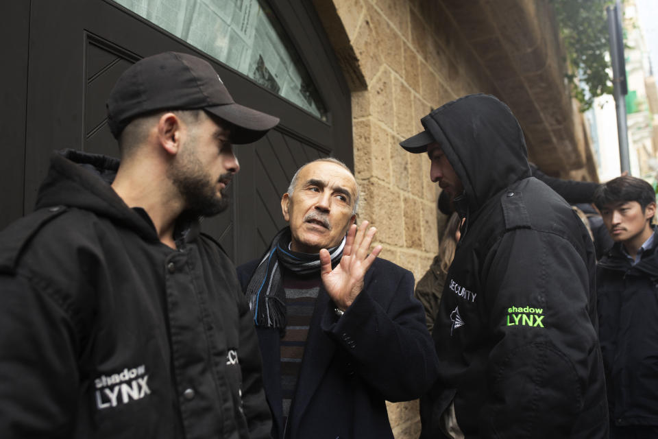 Private security guards flank a man who identified himself as a family doctor speaks to journalists as he enters the home of former Nissan Chairman Carlos Ghosn in Beirut, Lebanon, Thursday, Jan. 2, 2020. Turkish authorities have detained seven people as part of an investigation into how Ghosn, who skipped bail in Japan, was able to flee to Lebanon via Istanbul, Turkish media reported Thursday. (AP Photo/Maya Alleruzzo)