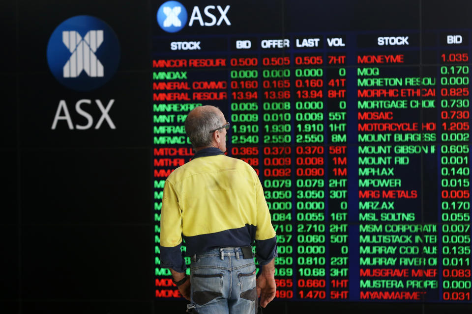 A man looks at an electronic board displaying stock information at the Australian Securities Exchange.