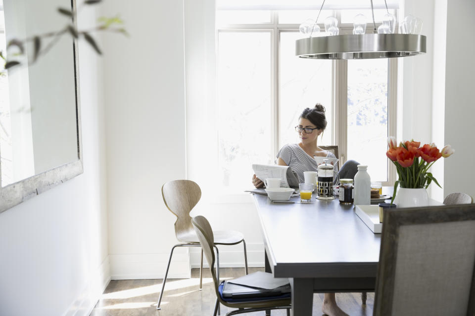 Woman reading newspaper at breakfast dining table