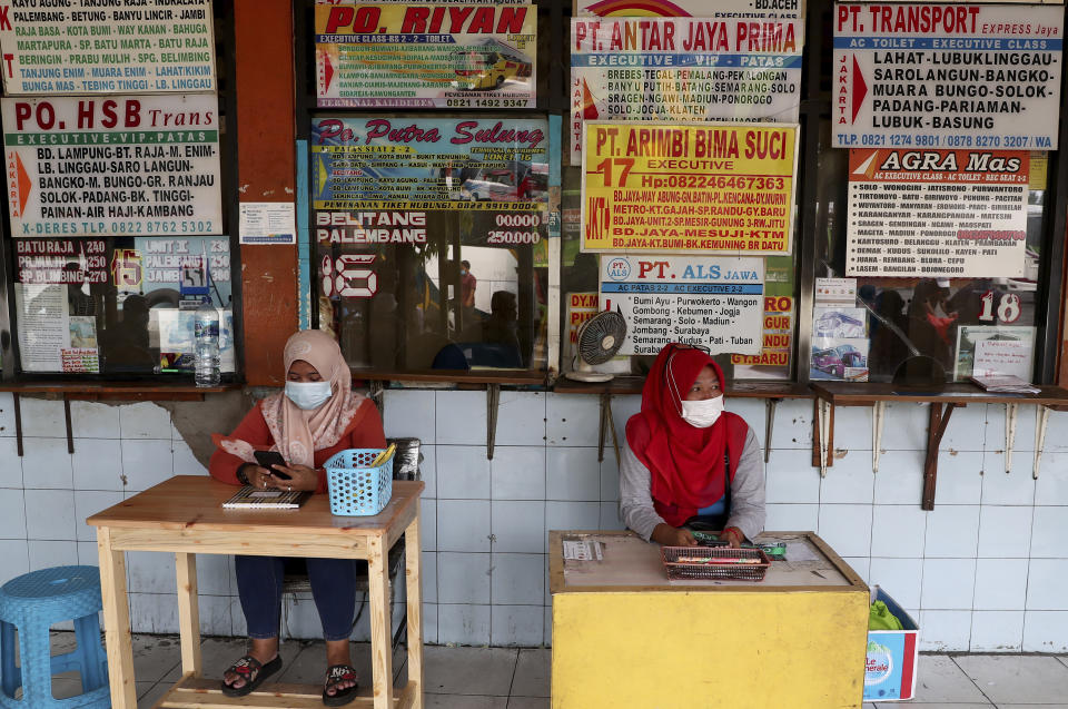 Employees wait for customers at the ticket counters at the Kalideres bus terminal in Jakarta, Indonesia, Wednesday, May 5, 2021. The mass exodus out of major cities in the world's most populous Muslim country is underway despite travel restrictions imposed by the government to prevent the spread of coronavirus outbreak, as people are heading home to their villages to celebrate Eid al-Fitr holiday that marks the end of the holy fasting month of Ramadan on May 13. (AP Photo/Tatan Syuflana)