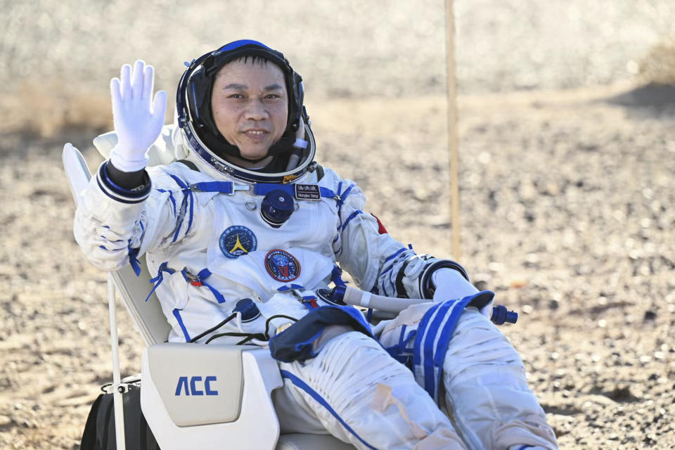 In this photo released by Xinhua News Agency, Tang Hongbo, a Chinese astronaut and a commander sits near the capsule of the Shenzhou-17 manned space mission waves after landing at the Dongfeng landing site in north China's Inner Mongolia Autonomous Region, Tuesday, April 30, 2024. China's Shenzhou-17 spacecraft returned to Earth Tuesday, carrying three astronauts who have completed a six-month mission aboard the country's orbiting space station. (Bei He/Xinhua via AP)