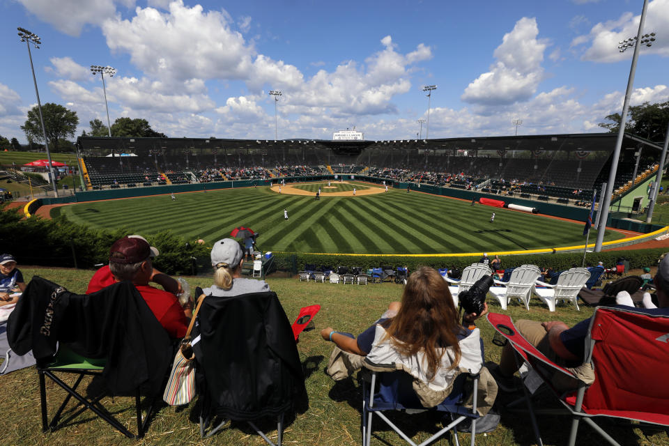 In this Aug. 23, 2018, photo, Little League fans watch a consolation baseball game between Coeur D'Alene, Idaho and Barcelona, Spain at the Little League World Series tournament in South Williamsport, Pa. Little League has been benched. The youth baseball program that boasts more than 2.5 million kids spread over 6,500 programs in 84 countries is on hold at least until May 11 due to the corona virus pandemic. Even that target date for a return to the sports lineup seems optimistic, and the fate of its signature event, the Little League World Series in August in South Williamsport, Pennsylvania is unclear. (AP Photo/Gene J. Puskar)