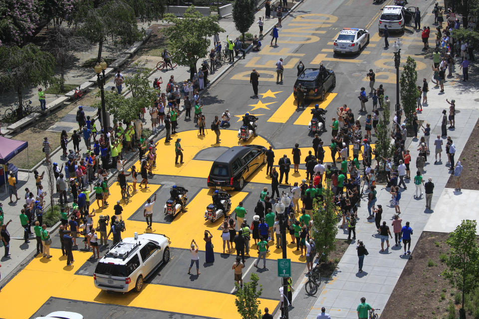 FILE - The hearse carrying the late Rep. John Lewis, D-Ga., moves along a section of 16th Street that's been renamed Black Lives Matter Plaza in Washington, July 27, 2020. The original mural bore a yellow outline of the district's flag — two horizontal lines topped by three stars. Within days, activists added their own message, turning the mural into “Black Lives Matter=Defund The Police.” (AP Photo/Pablo Martinez Monsivais, File)