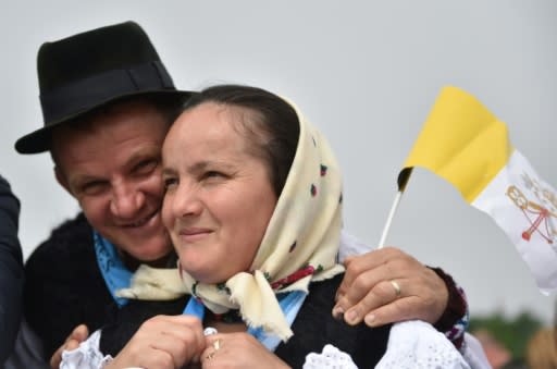 A Romanian couple in Blaj hold a Vatican flag as they attend Pope Francis's mass