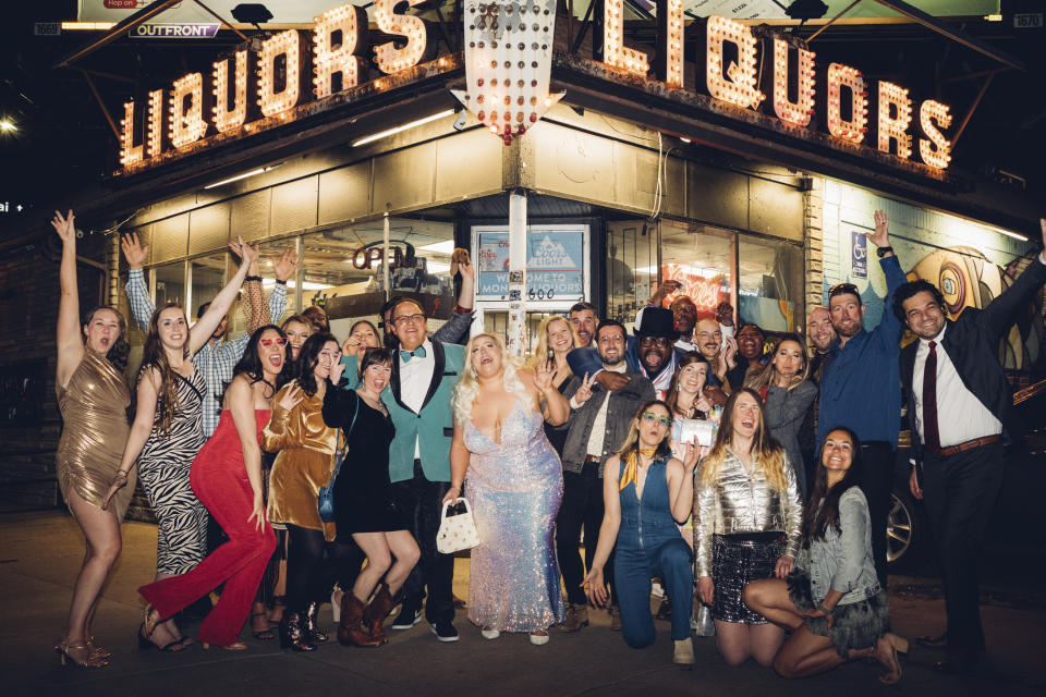 CORRECTS LOCATION TO DENVER - Wedding guest Maggie Long, left, poses in a group photo with others including groom Travis Holquin, in green tux center left, and bride Hannah Holquin, silver gown in center, at a dive bar themed wedding in Denver on April 1, 2023. (Bre Holligan Photography via AP)