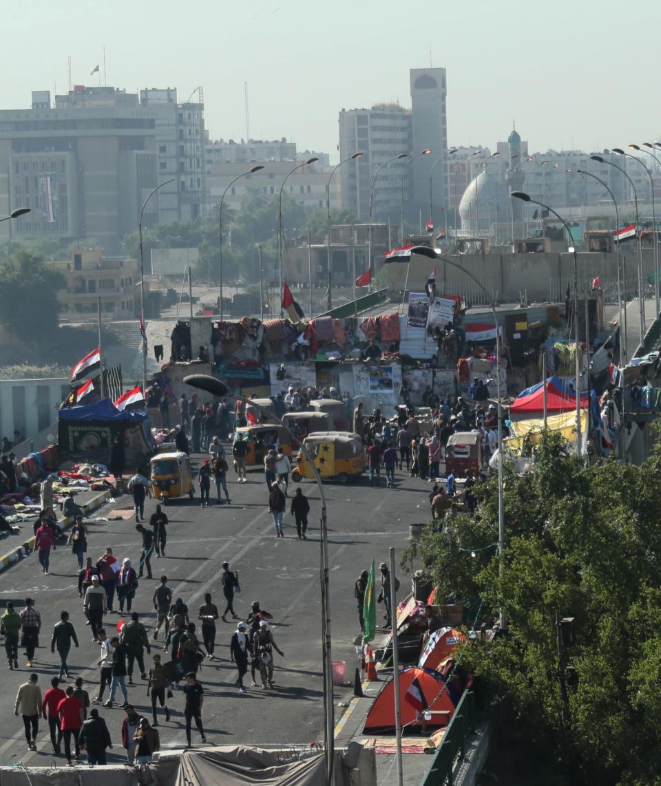 Protesters stage a sit-in at barriers on the Sinak Bridge while security forces stand guard behind concrete walls, in Baghdad, Iraq, Thursday, Nov. 21, 2019. Renewed clashes overnight in Baghdad between anti-government demonstrators and security forces killed and wounded protesters, security and hospital officials said Thursday. (AP Photo/Hadi Mizban)