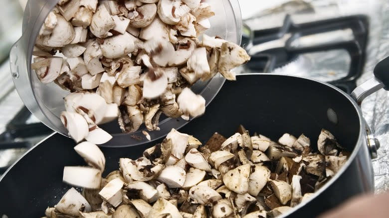 Putting chopped raw mushrooms in a pan