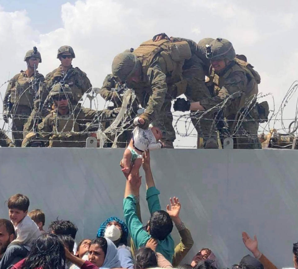 A baby being lifted across a wall at Kabul Airport in Afghanistan by US soldiers. She was later reunited with her parents. Source: Omar Haidari via AP
