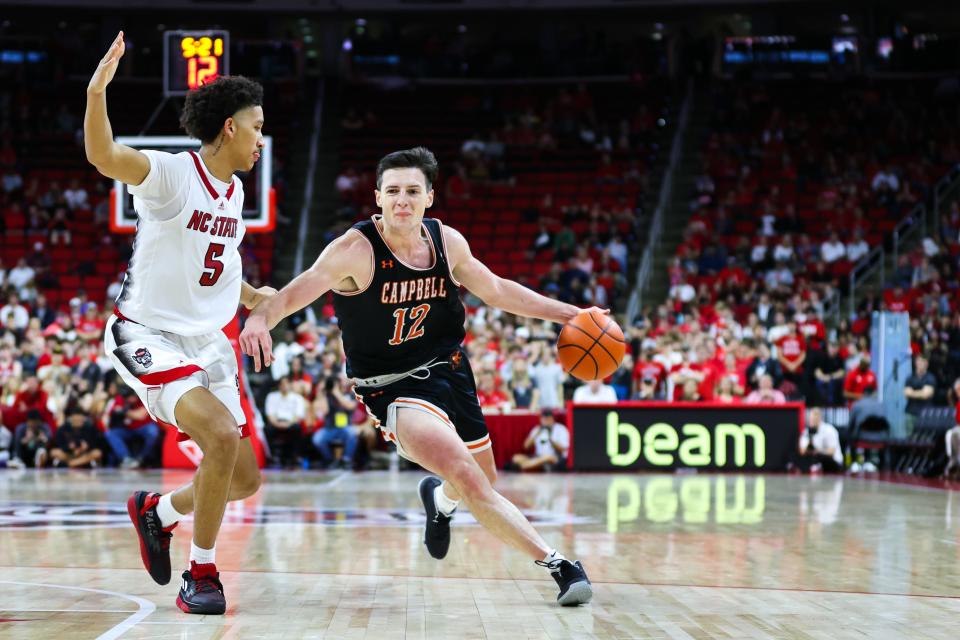 Campbell Fighting Camels forward Jesus Carralero (12) runs with the ball while guard Jack Clark (5) guards him during the second half against North Carolina State Wolfpack at PNC Arena.