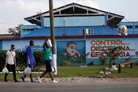 People pass by an image of Cuba's President Raul Castro in Havana, Cuba, December 21, 2017. REUTERS/Stringer/Files