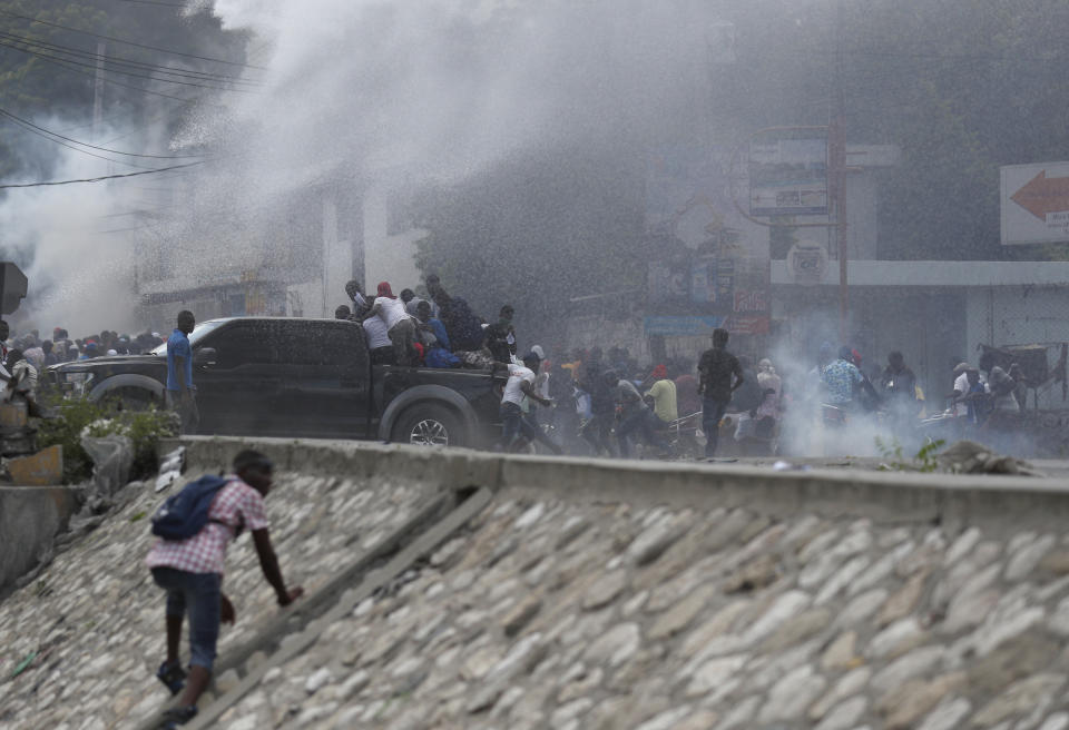 Demonstrators are sprayed by a police water cannon during a protest calling for the resignation of President Jovenel Moise, in Port-au-Prince, Haiti, Friday, Oct. 4, 2019. After a two-day respite from the recent protests that have wracked Haiti's capital, opposition leaders urged citizens angry over corruption, gas shortages, and inflation to join them for a massive protest march to the local headquarters of the United Nations. (AP Photo/Rebecca Blackwell)