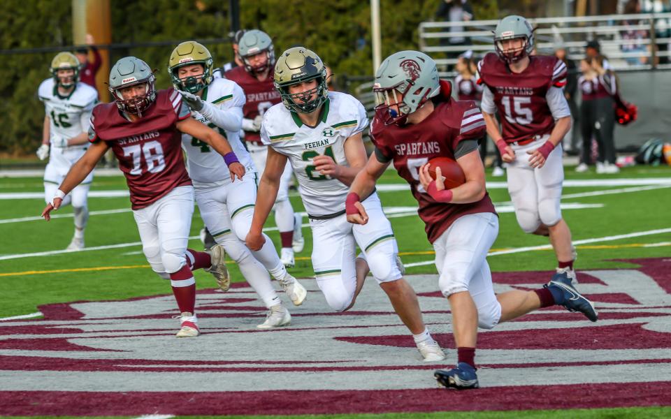 Nick Hyland of Bishop Stang carries the ball past mid field as Dylan Hackett of Bishop Feehan looks to make a tackle on the play.