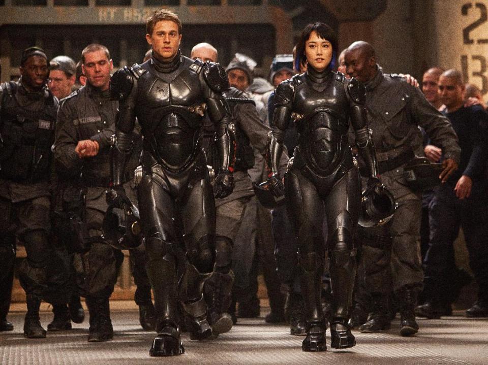 This publicity photo released by Warner Bros. Pictures shows, front from left, Charlie Hunnam as Raleigh Becket and Rinko Kikuchi as Mako Mori in Warner Bros. Pictures’ and Legendary Pictures’ sci-fi action adventure, “Pacific Rim,” a Warner Bros. Pictures release. (AP Photo/Warner Bros. Pictures, Kerry Hayes)