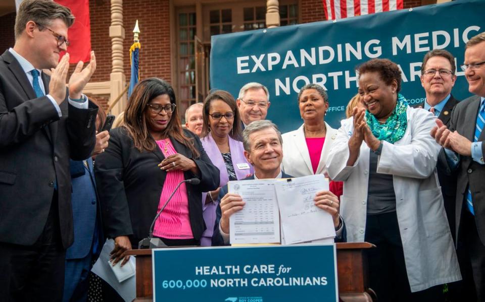 Gov. Roy Cooper holds up the Medicaid expansion bill after signing it into law during a ceremony at the Executive Mansion Monday, March 27, 2023.
