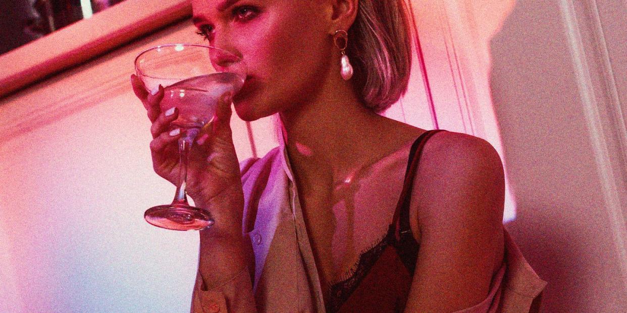 a chic woman drinking a cocktail bathed in neon light