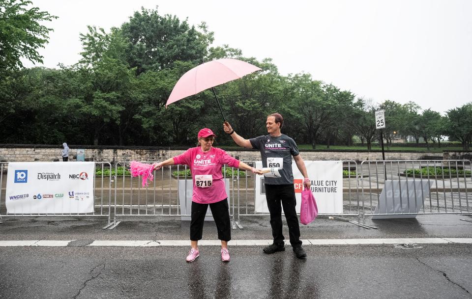 Breast cancer survivor Lydia Kemerling Back dances in the rain to Bruno Mars while her husband Johnny Back holds an umbrella over her head before the start of the 2023 Komen Columbus Race for the Cure.