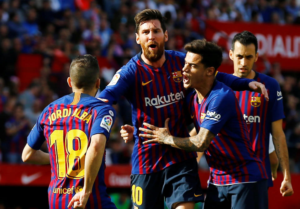 Lionel Messi is mobbed by his Barcelona teammates after scoring an amazing opening goal against Sevilla, his first of three in the 4-2 win. (Reuters/Marcelo del Pozo)