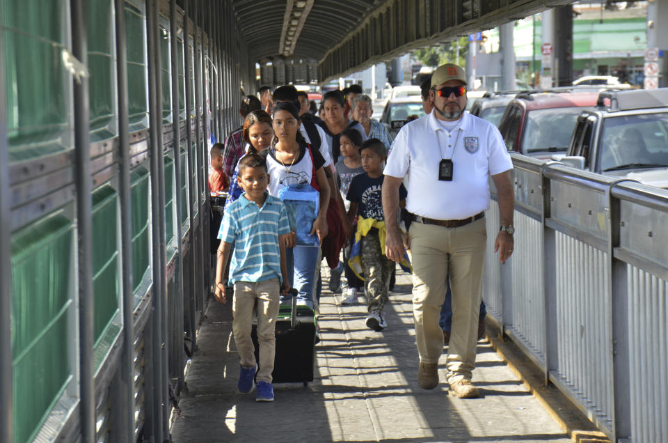 A Mexican migration officer escorts a group of migrants to apply for asylum in the United States, on the International Bridge 1 in Nuevo Laredo, Mexico, Wednesday, July 17, 2019. Asylum-seekers grappled to understand what a new U.S. policy that all but eliminates refugee claims by Central Americans and many others meant for their bids to find a better life in America amid a chaos of rumors, confusion and fear. (AP Photo/Salvador Gonzalez)