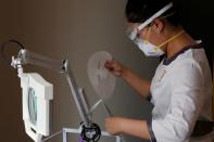 Beautician wearing protective mask and goggles takes out a facial mask during treatment at the Pearl Deluxe beauty spa in Beijing