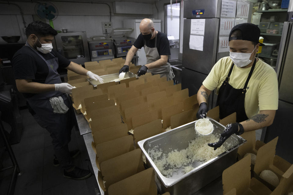 Volunteers of COVID Thailand Aid, chef Lorin Janita from the U.S., left, chef Tim Butler of the U.S., center and chef Napol Jantraget from Thailand, right, prepare meal for the railway-side community at Bo.lan restaurant in Bangkok, Thailand Wednesday, June 10, 2020. Thailand's Natalie Bin Narkprasert, who runs a business in Paris, was stranded in her homeland by a flight ban, so she decided to use her skills to organize the network of volunteers, including Michelin-starred chefs, to help those in her homeland whose incomes were most affected by the pandemic restrictions. (AP Photo/Sakchai Lalit)