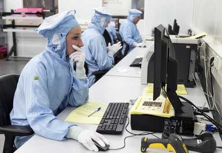 A female employee wearing special clothing and footwear works at the ASML factory in Veldhoven January 17, 2013. REUTERS/Michael Kooren