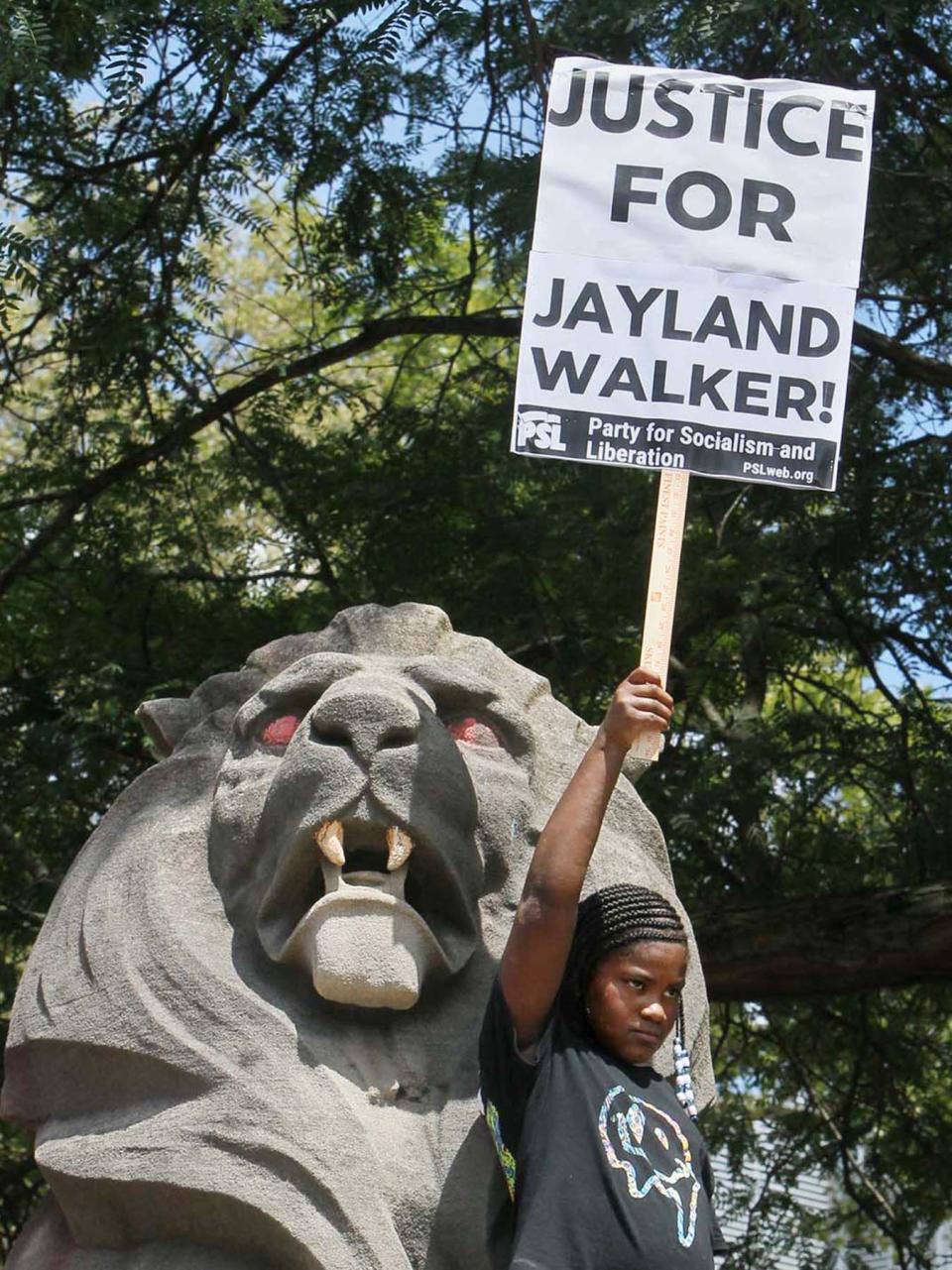 A young activist holds a sign in front of one of the lions at the Summit County Courthouse during a protest of the police shooting of Jayland Walker organized by the Party for Socialism and Liberation on July 9, 2022, in Akron. (Karen Schiely, Akron Beacon Journal)
