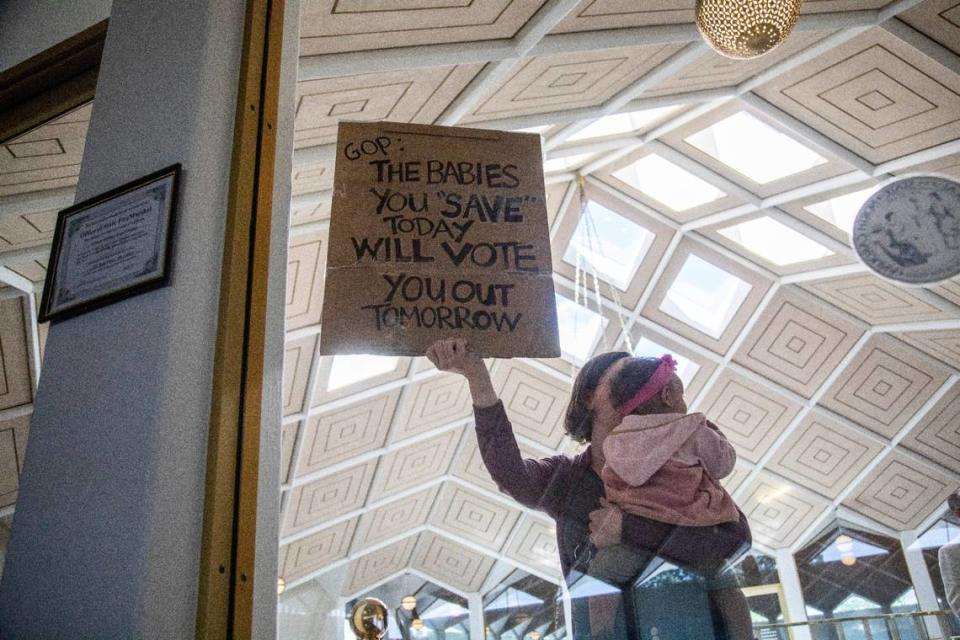 A demonstrator holds a sign and a baby outside a House Floor gallery window at the North Carolina State Legislature after Republican state lawmakers announced their plan to limit abortion rights across the state.