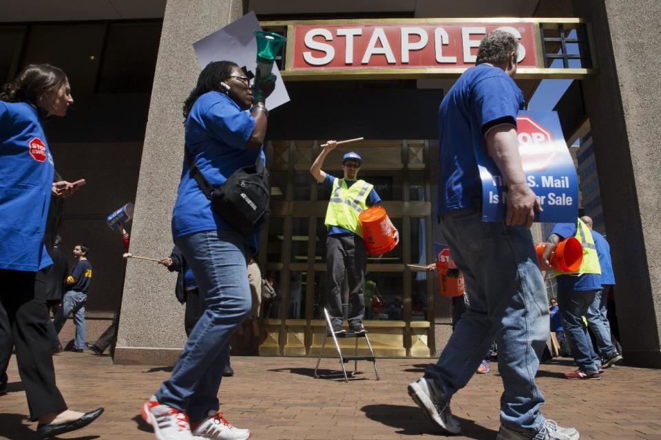 Matt Kent, with the American Postal Workers Union, center, beats rhythms on a bucket as he and other union members protest a deal between the U.S. Postal Service and Staples that will privatize USPS retail services, Thursday, April 24, 2014, outside a Staples store in downtown Washington. Postal workers are protesting the opening of postal counters in Staples stores that are staffed with retail employees. Thursday's protests are planned at 50 locations in 27 states, including rallies in New York, Los Angeles and Washington. (AP Photo/Jacquelyn Martin)