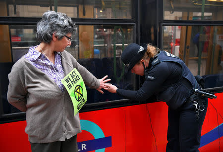 A police officer tries to remove the hand of protester Diana Warner, glued to a train, as demonstrators block traffic at Canary Wharf Station during the Extinction Rebellion protest in London, Britain April 25, 2019. REUTERS/Dylan Martinez