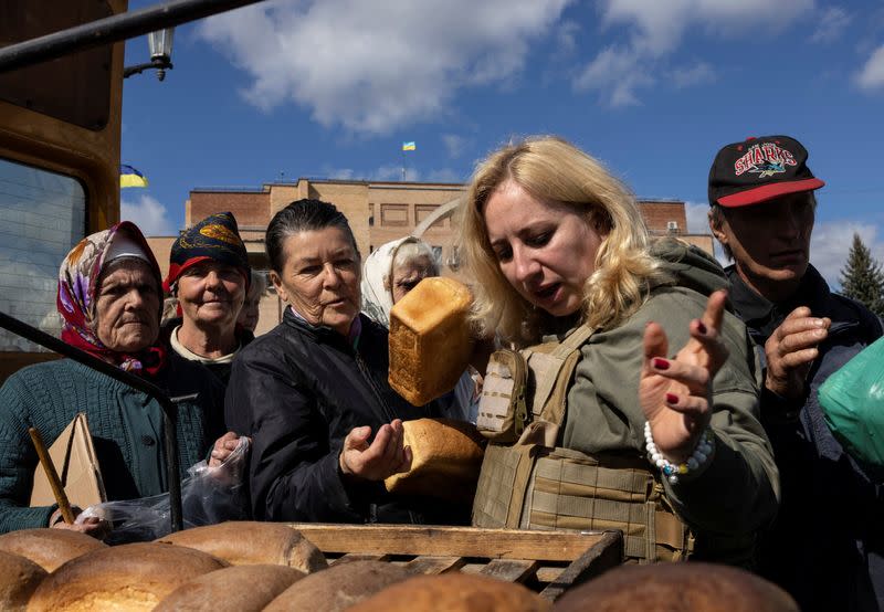 FILE PHOTO: Locals wait in line for bread, candles and food provided by aid workers as there is no electricity in Balakliia