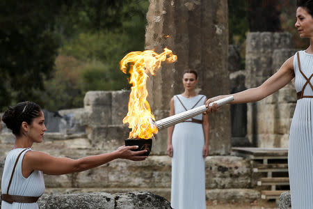 Olympics - Lighting Ceremony of the Olympic Flame Pyeongchang 2018 - Ancient Olympia, Olympia, Greece - October 24, 2017 Greek actress Katerina Lehou, playing the role of High Priestess with the flame on the torch during the Olympic flame lighting ceremony for the Pyeongchang 2018 Winter Olympics REUTERS/Alkis Konstantinidis