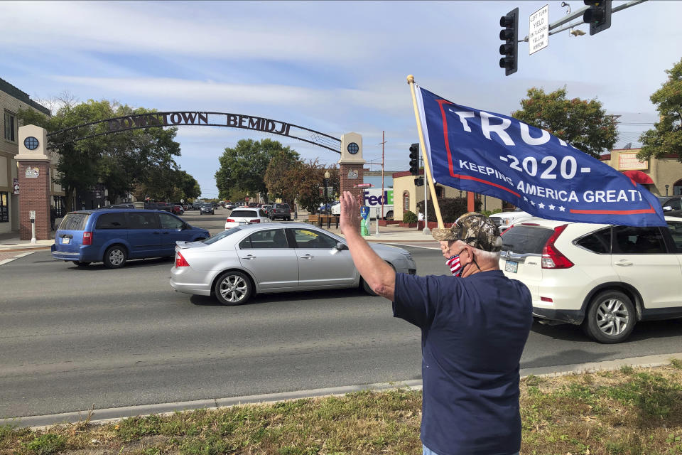 A supporter of President Donald Trump waves to passing cars Friday, Sept. 18, 2020 in Bemidji, Minn., where the President is slated to hold a campaign rally at the airport in the early evening. (AP Photo/Jim Mone)