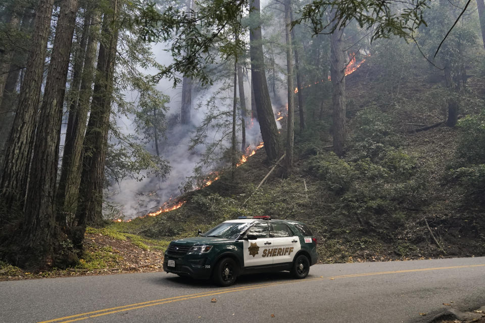 A police vehicle is seen under a forest being burned by the CZU August Lightning Complex Fire Monday, Aug. 24, 2020 near in Bonny Doon, Calif. (AP Photo/Marcio Jose Sanchez)