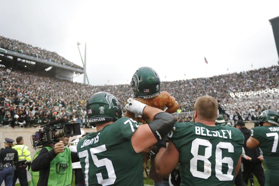 Michigan State defensive end Drew Beesley (86) and guard Kevin Jarvis (75) carry the Paul Bunyan trophy to celebrate the 37-33 win over Michigan at Spartan Stadium in East Lansing on Saturday, Oct. 30, 2021. 