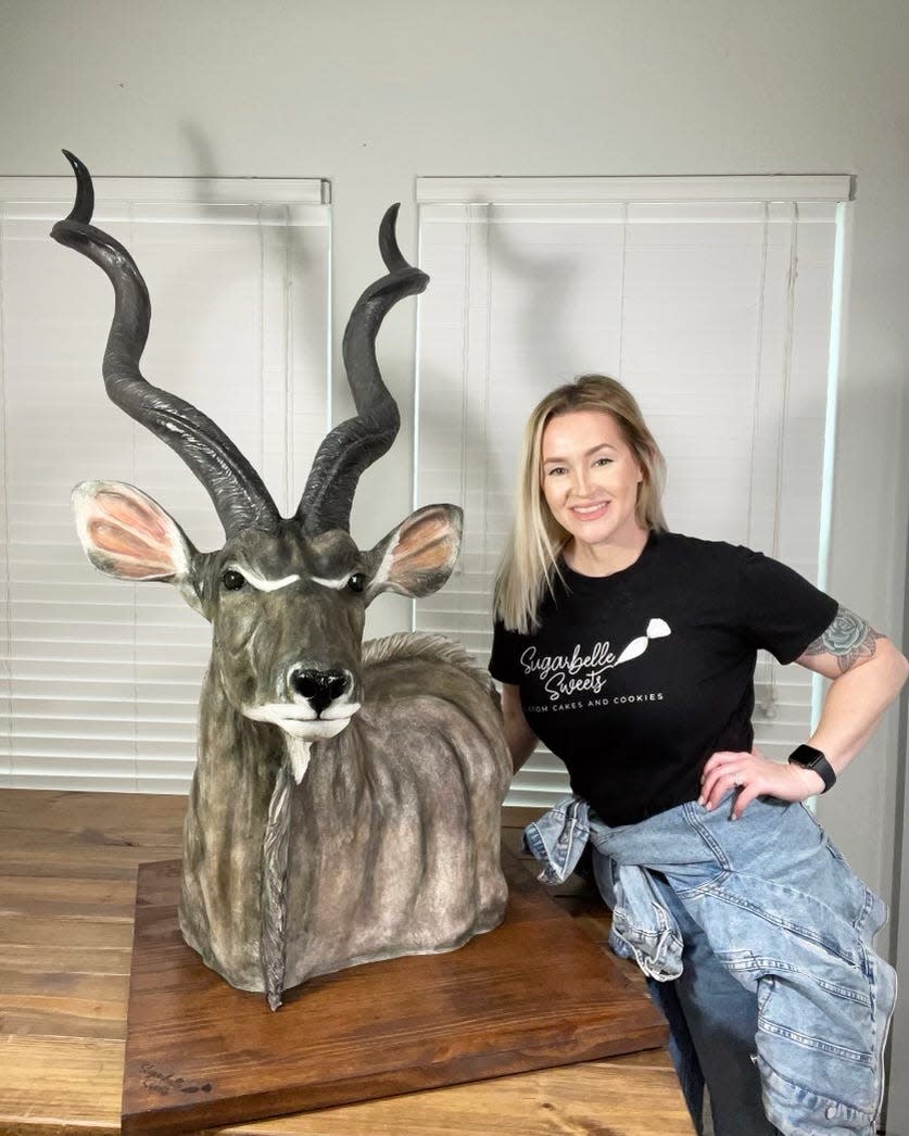 Dusty Sinclair of Corpus Christi, owner of Sugarbelle Sweets, poses with a cake sculpture of a greater kudu. Since 2020, Sinclair has specialized in creating realistic hunting and fishing inspired cakes for weddings and large events.