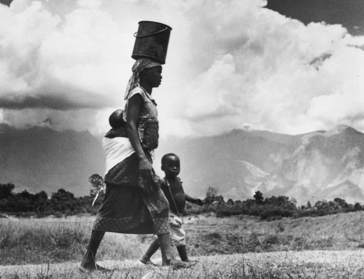 Collecting water and caring for kids are daily necessities. <a href="https://www.gettyimages.com/detail/news-photo/rhodesian-woman-carries-her-baby-on-her-back-and-a-pail-of-news-photo/56650474" rel="nofollow noopener" target="_blank" data-ylk="slk:Three Lions/Hulton Archive via Getty Images;elm:context_link;itc:0;sec:content-canvas" class="link ">Three Lions/Hulton Archive via Getty Images</a>