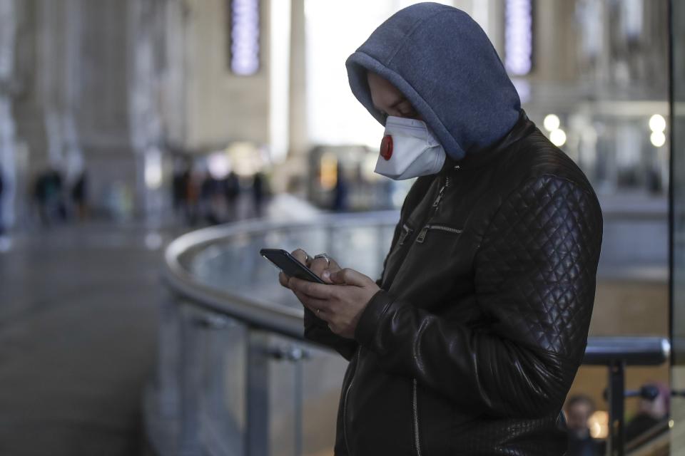 A man wearing a sanitary mask holds a smartphone at the Centrale main railway station in Milan, Italy, Monday, Feb. 24, 2020. Italy has been scrambling to check the spread of Europe's first major outbreak of the new viral disease amid rapidly rising numbers of infections and a third death, calling off the popular Venice Carnival, scrapping major league soccer matches in the stricken area and shuttering theaters, including Milan's legendary La Scala. (AP Photo/Luca Bruno)