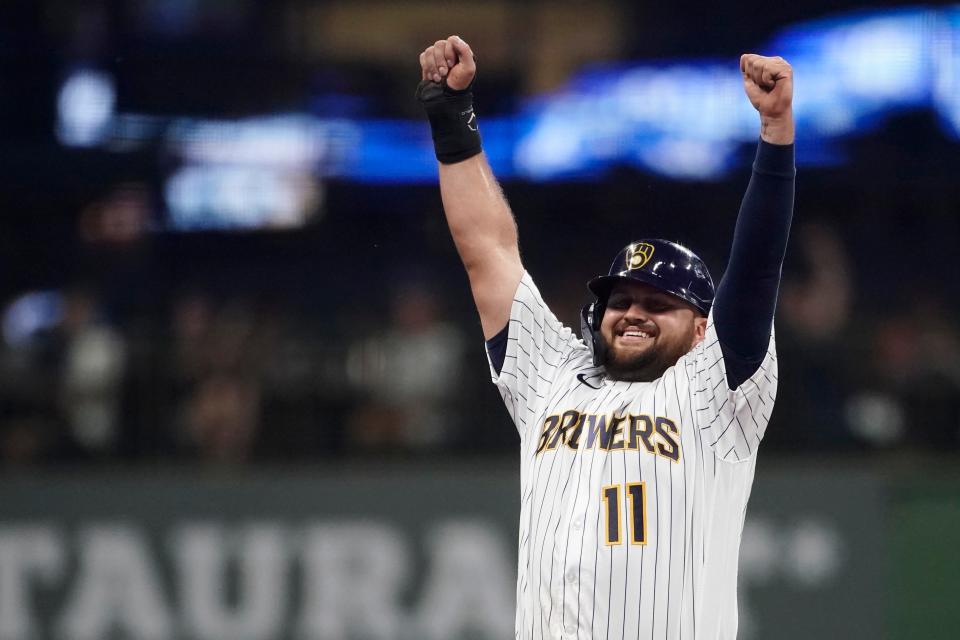 A smiling Rowdy Tellez raises his arms in celebration as he looks into the Brewers dugout after stealing second base against the Reds during the third inning Friday night.