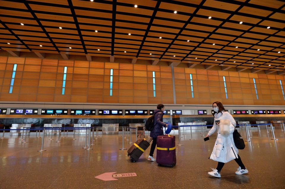Travelers walk through an almost empty departures area at the international terminal at Logan International Airport in Boston on Friday. (Joseph Prezioso / AFP via Getty Images)