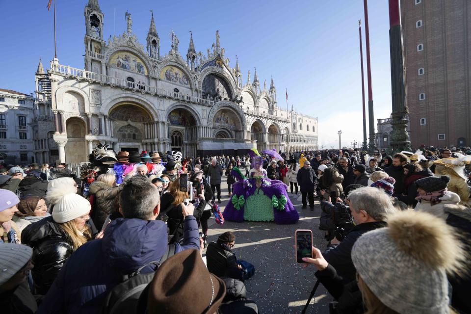 A woman wearing a mask poses in front of the St. Marks church during the Venice Carnival in Venice, Italy, Sunday Jan. 28, 2024. Venice is marking the 700th anniversary of the death of Marco Polo with a yearlong series of commemorations, starting with the opening of Carnival season honoring one of the lagoon city's most illustrious native sons. (AP Photo/Luca Bruno)